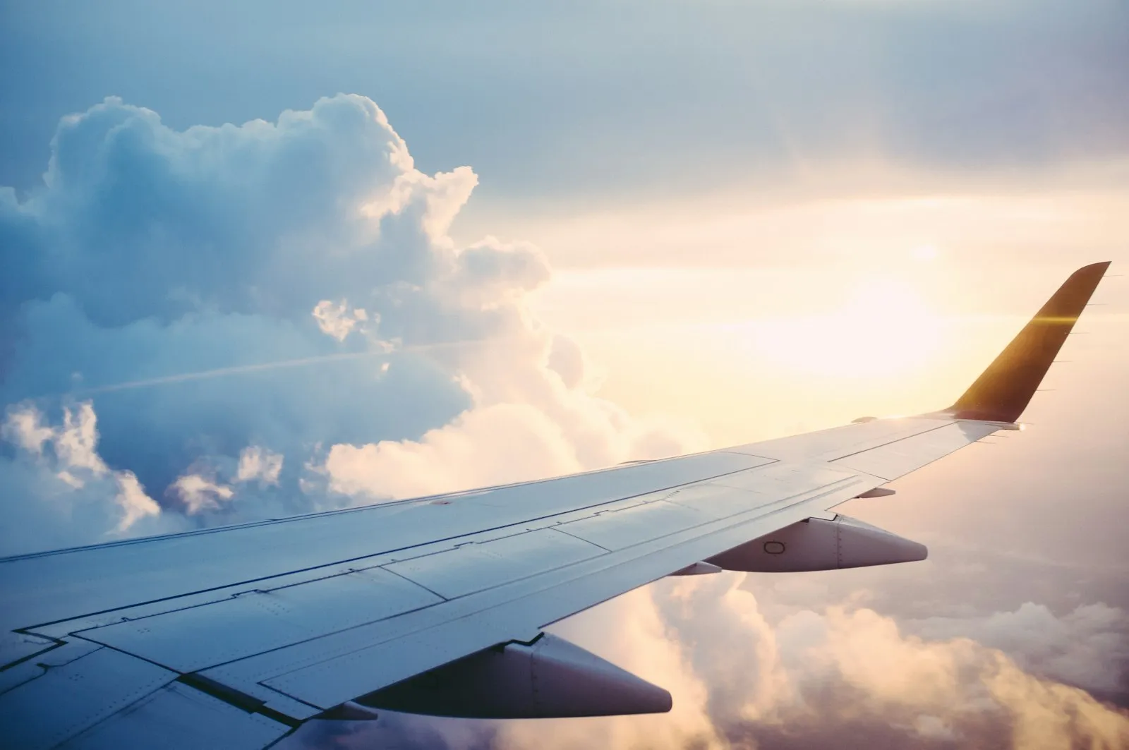 An airplane wing above clouds, the view between cities on a roadshow